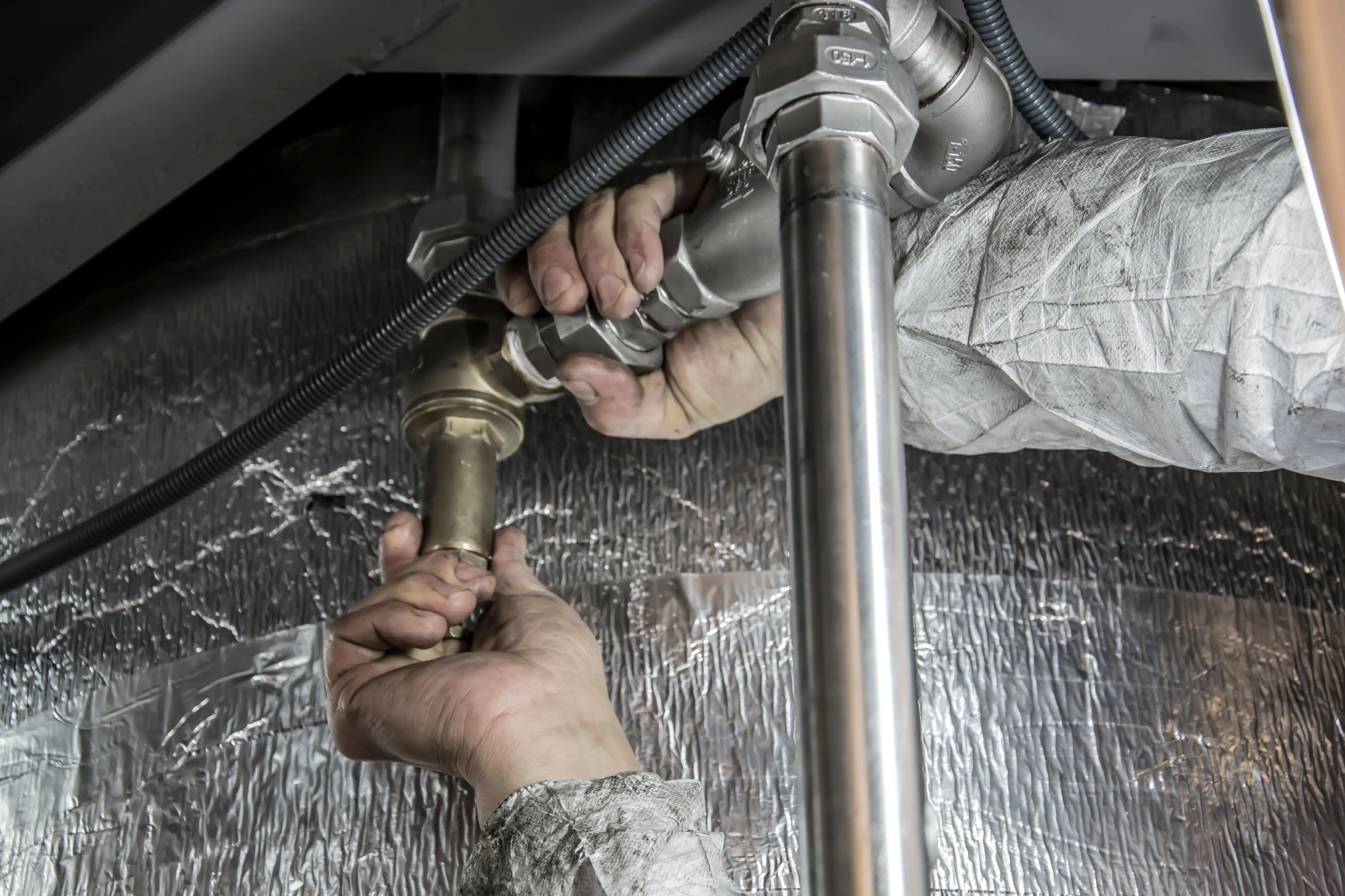 Plumber tightening pipe fittings during a burst pipe repair